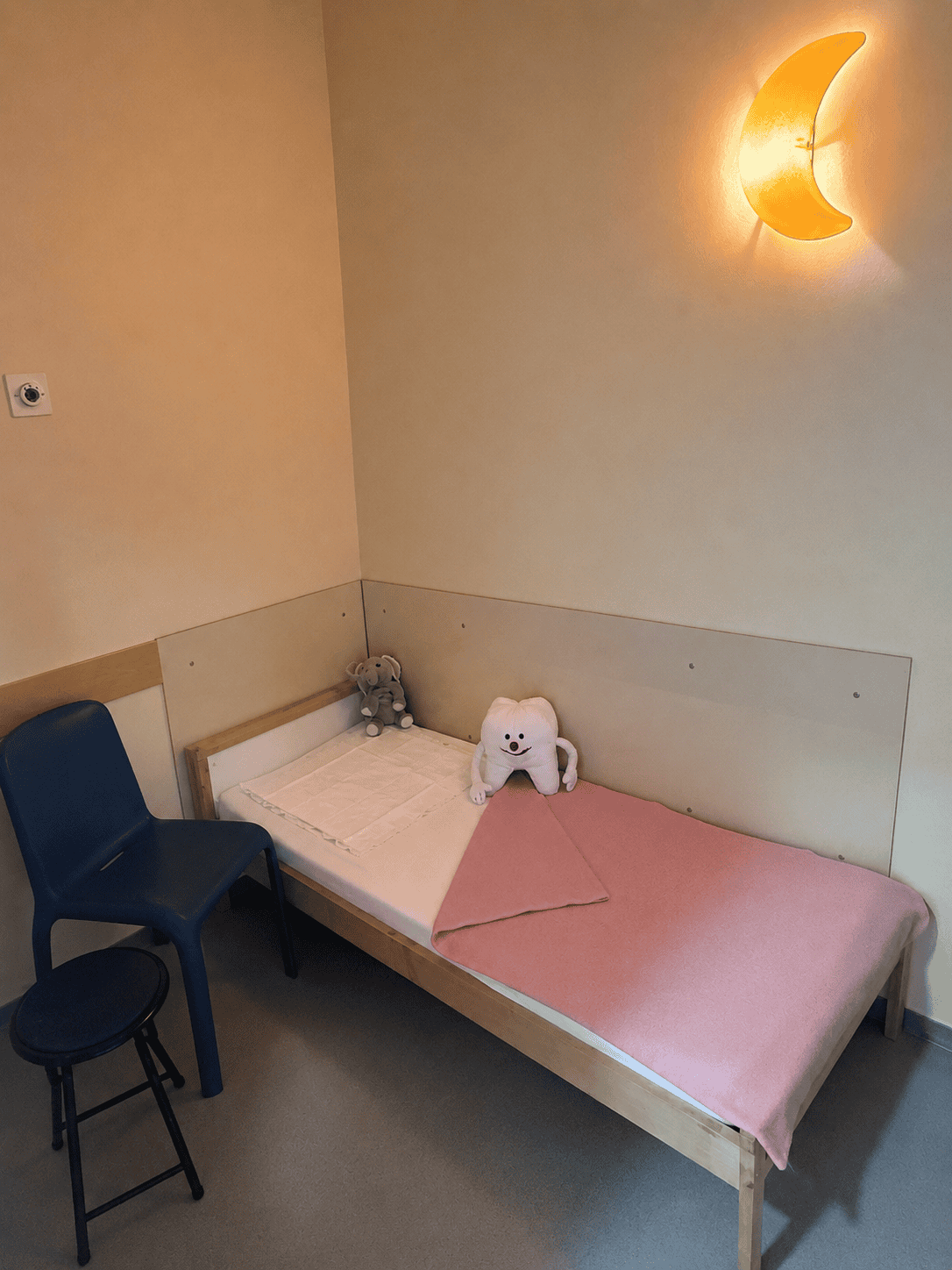 Kindgerecht gestalteter Aufwachraum mit Liege, Stofftieren und beleuchteter Mondlampe